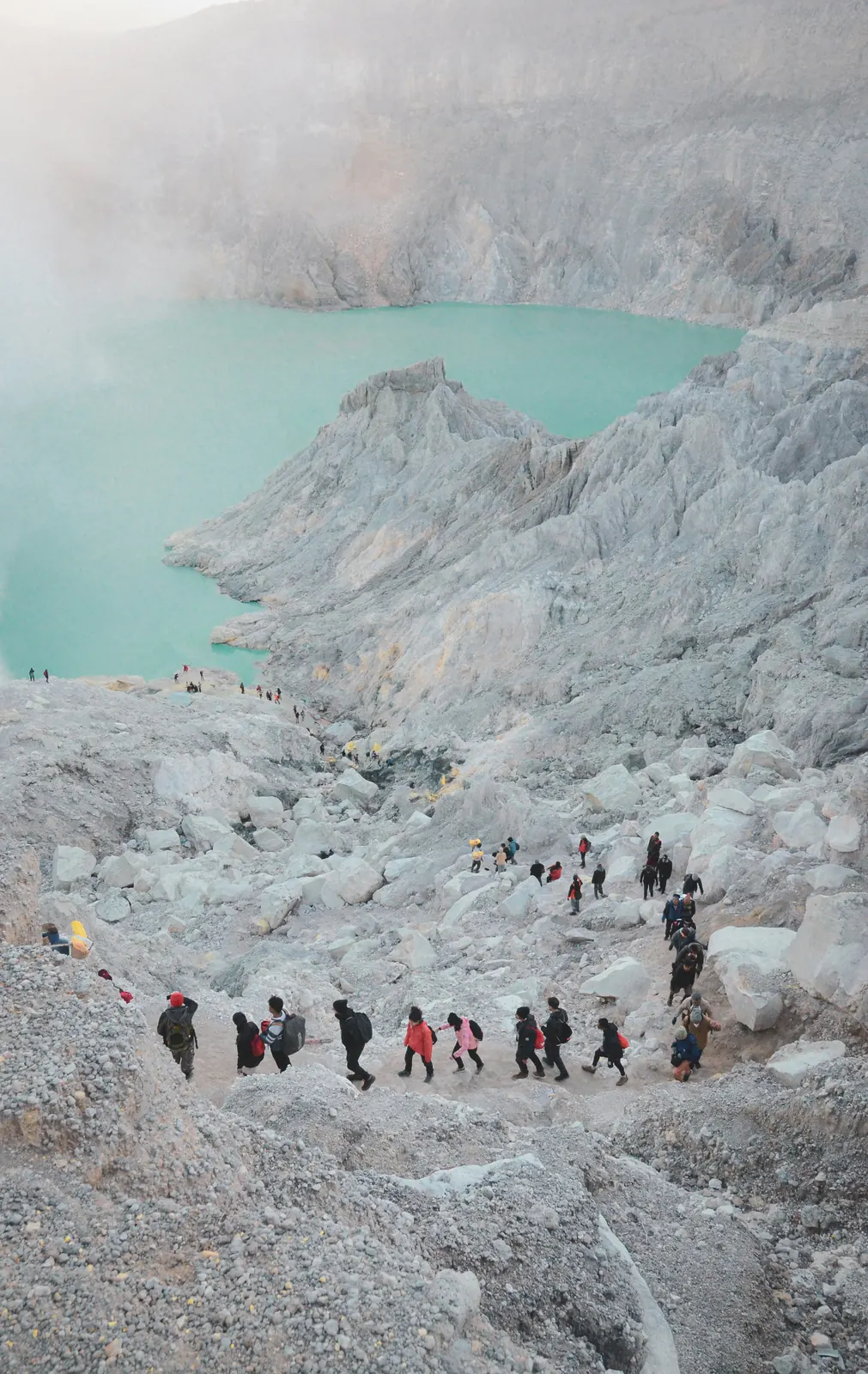 Hikers walking down into the Kawah Ijen crater towards its turquoise lake