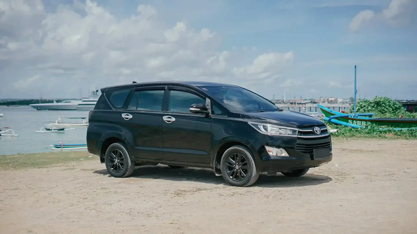 A black Toyota Innova parked by a harbour