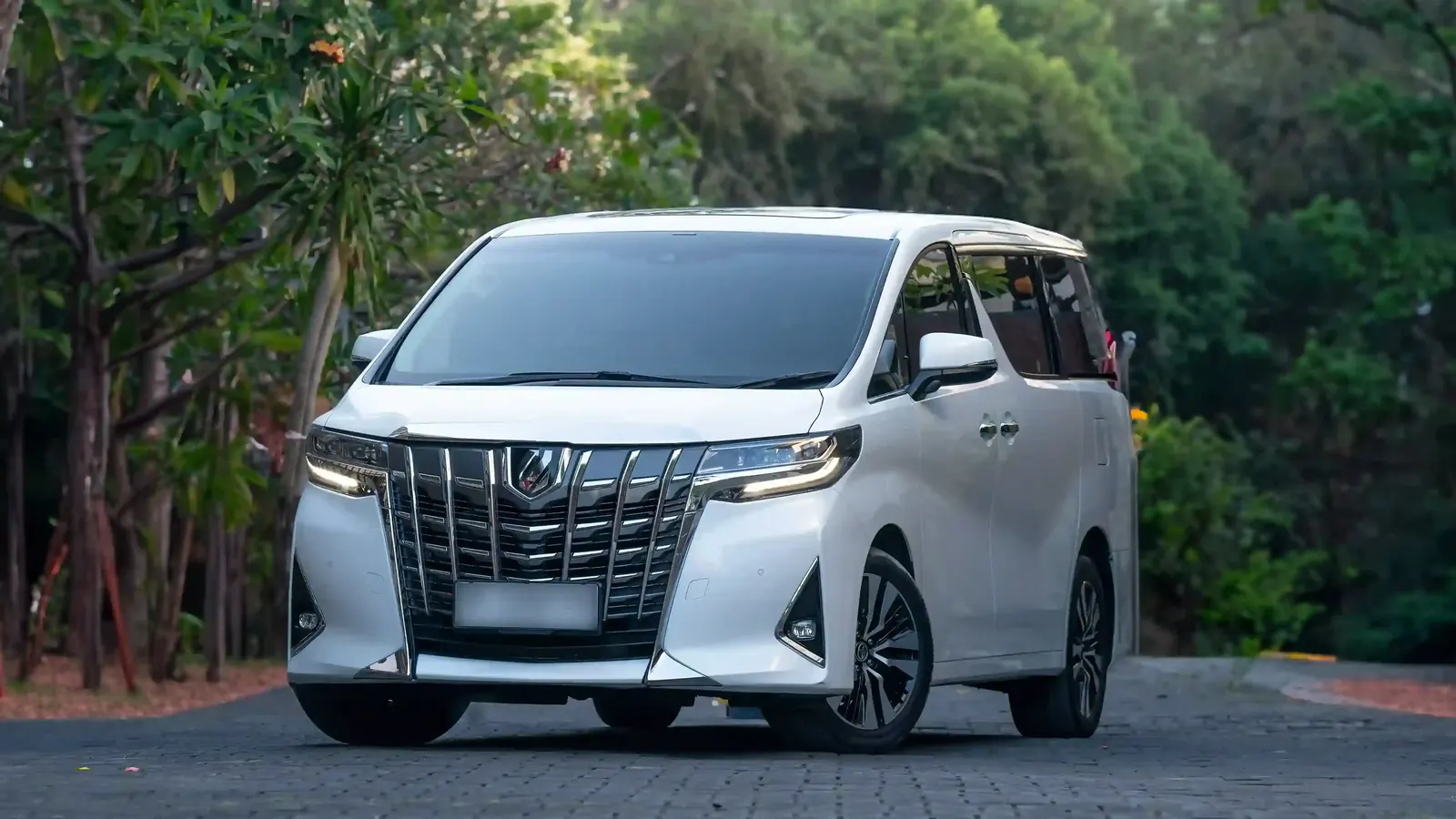A white Toyota Alphard minivan on a road