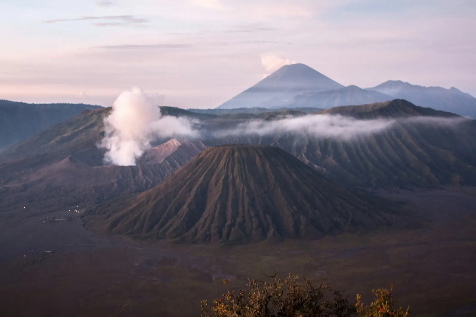 Smoke rising from Mount Bromo crater beside Mount Batok, Mount Semeru behind