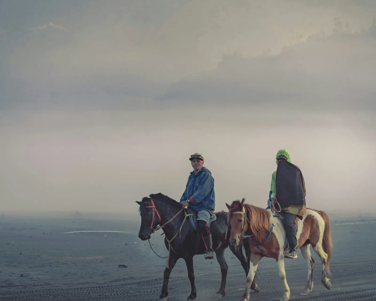 Two Tengger horsemen on the Bromo sea of sand in morning mist