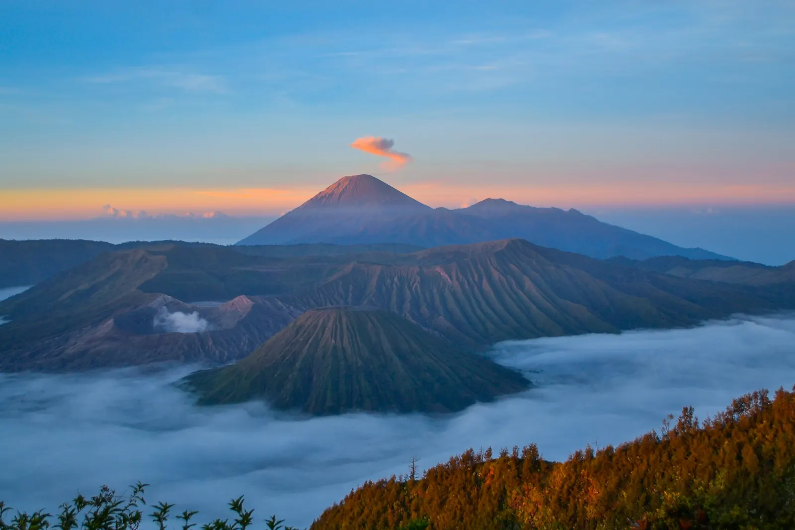 Mount Bromo and Mount Batok above a sea of cloud at sunrise, Semeru venting behind